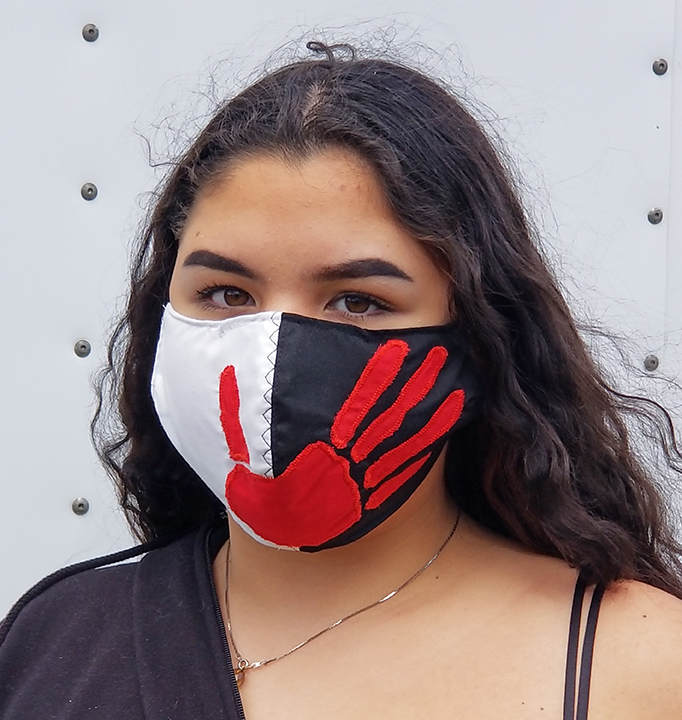 Model wearing black and white mask with red handprint design